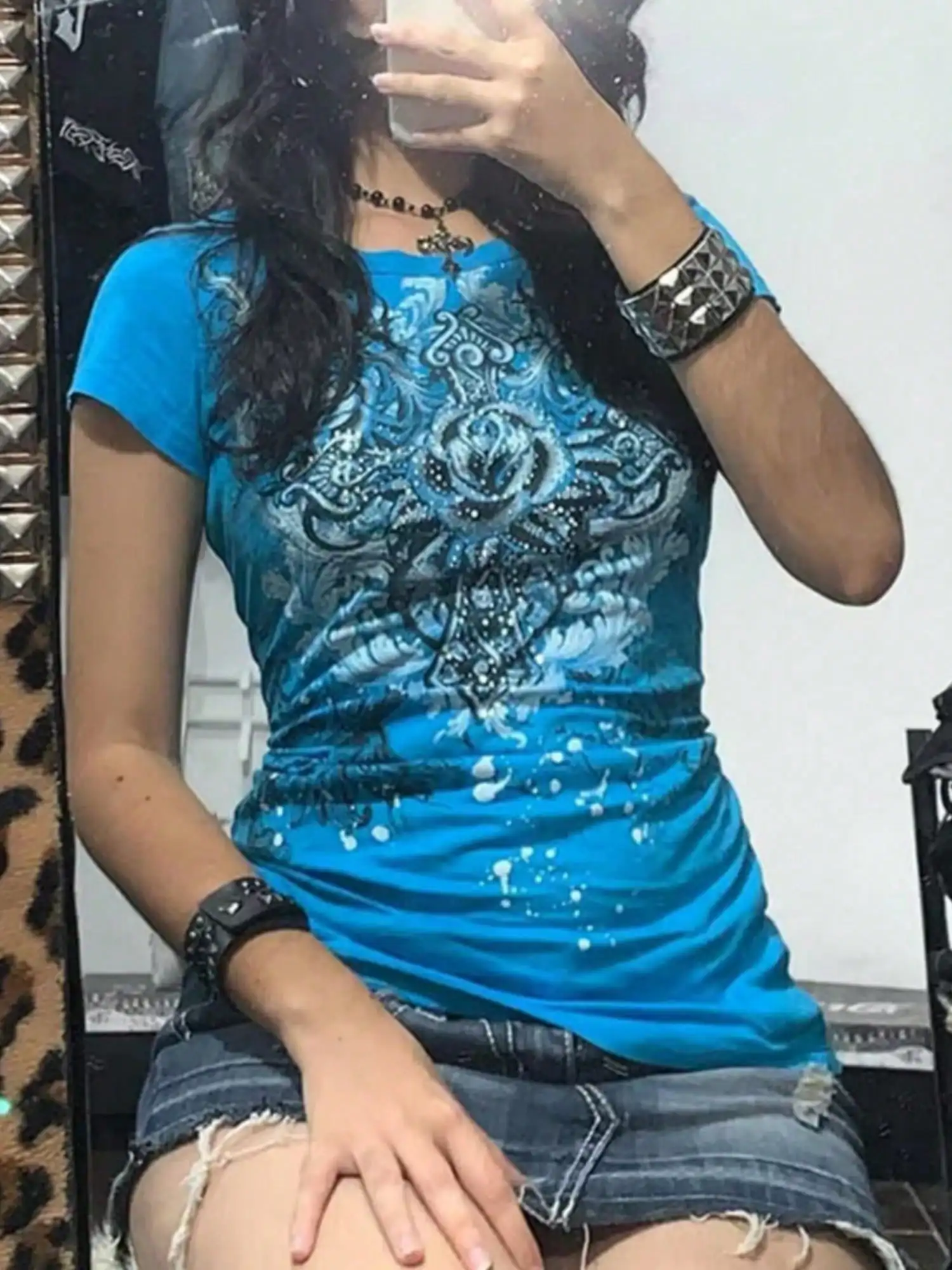 

Женская синяя футболка с коротким рукавом и круглым вырезом, с графическим принтом и цветочным узором.