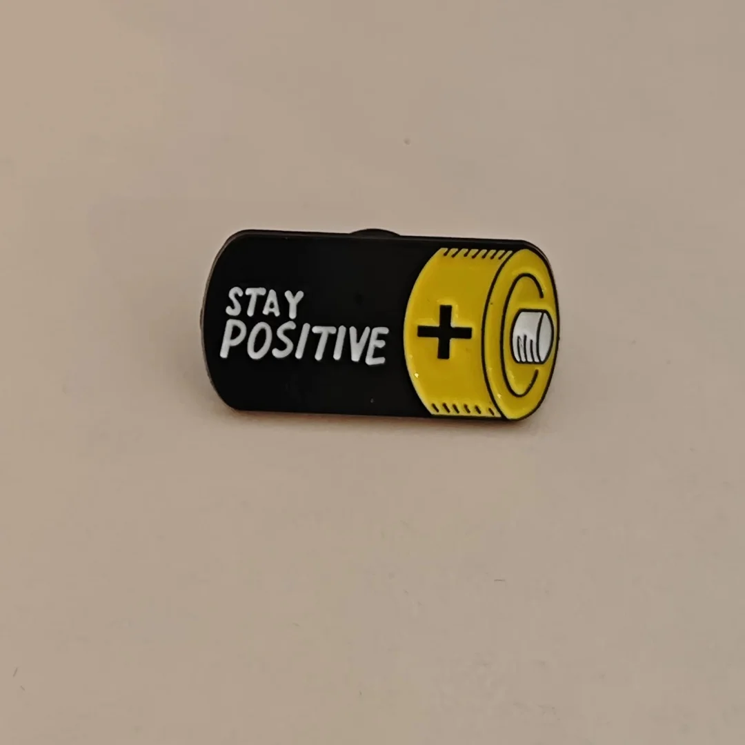 A unique and niche brooch in a battery style, promoting optimism for daily wear by men and women.