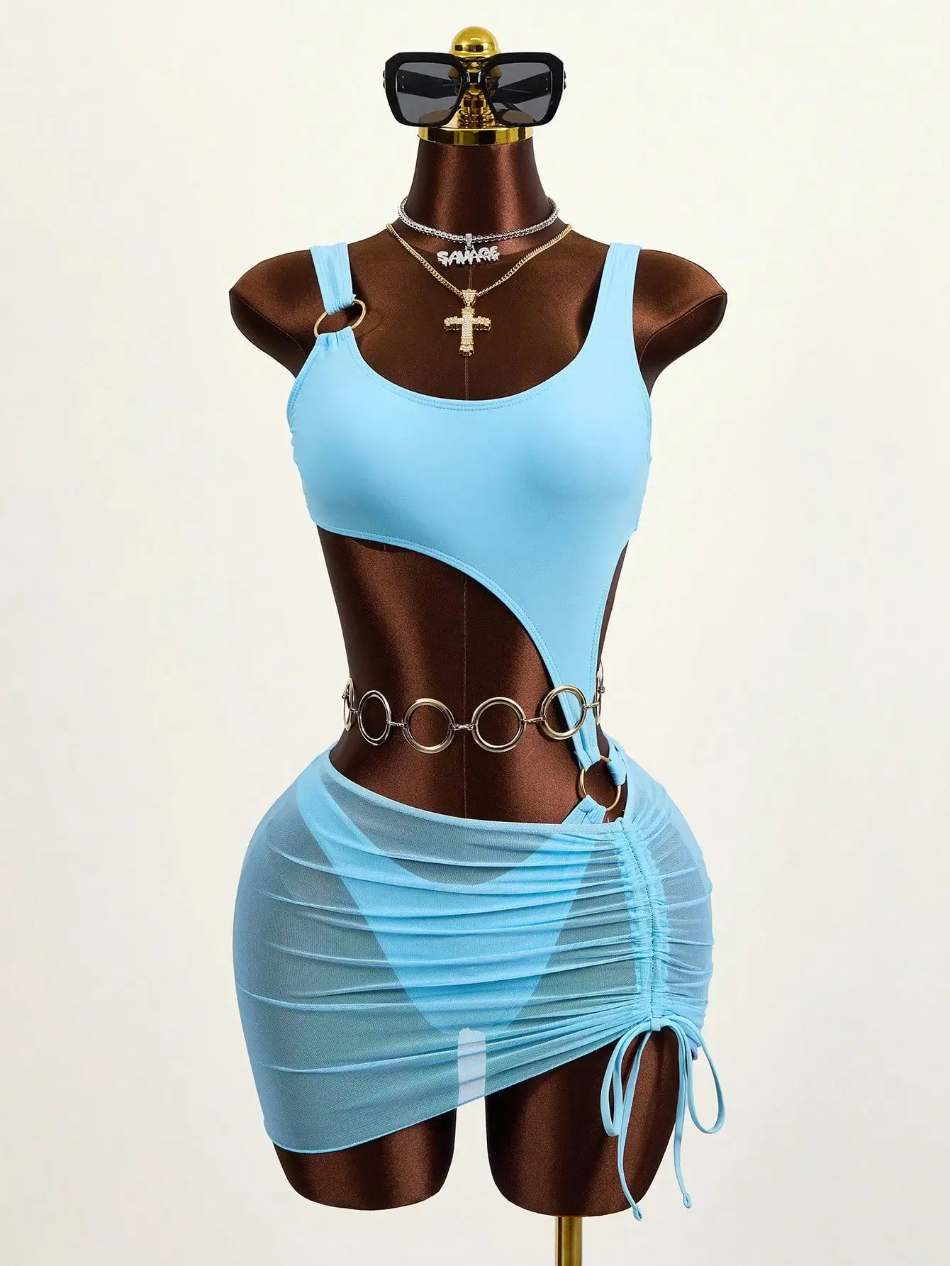 

Светло-голубой слитный купальник с вырезами по бокам, металлическими кольцами и прозрачной юбкой-накидкой с драпировкой