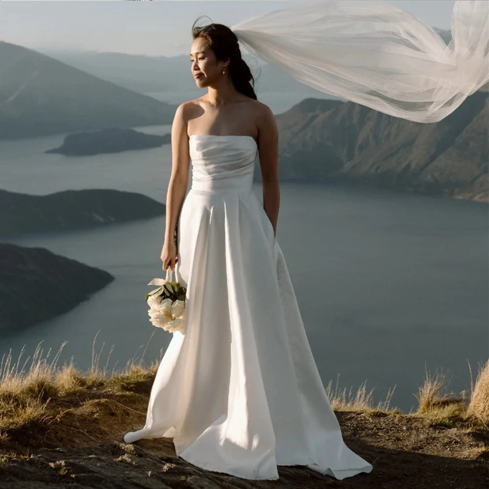 

Свадебное платье на заказ, атласное длинное свадебное платье без бретелек с рюшами и открытой спиной, трапециевидной формы с карманами, свадебные платья длиной до пола 2024