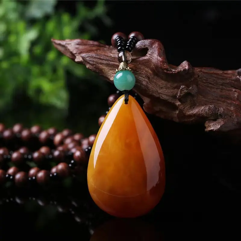 Vintage amber necklace with a long, teardrop-shaped pendant featuring a chicken oil yellow color, a Pixiu charm, and a safety cl