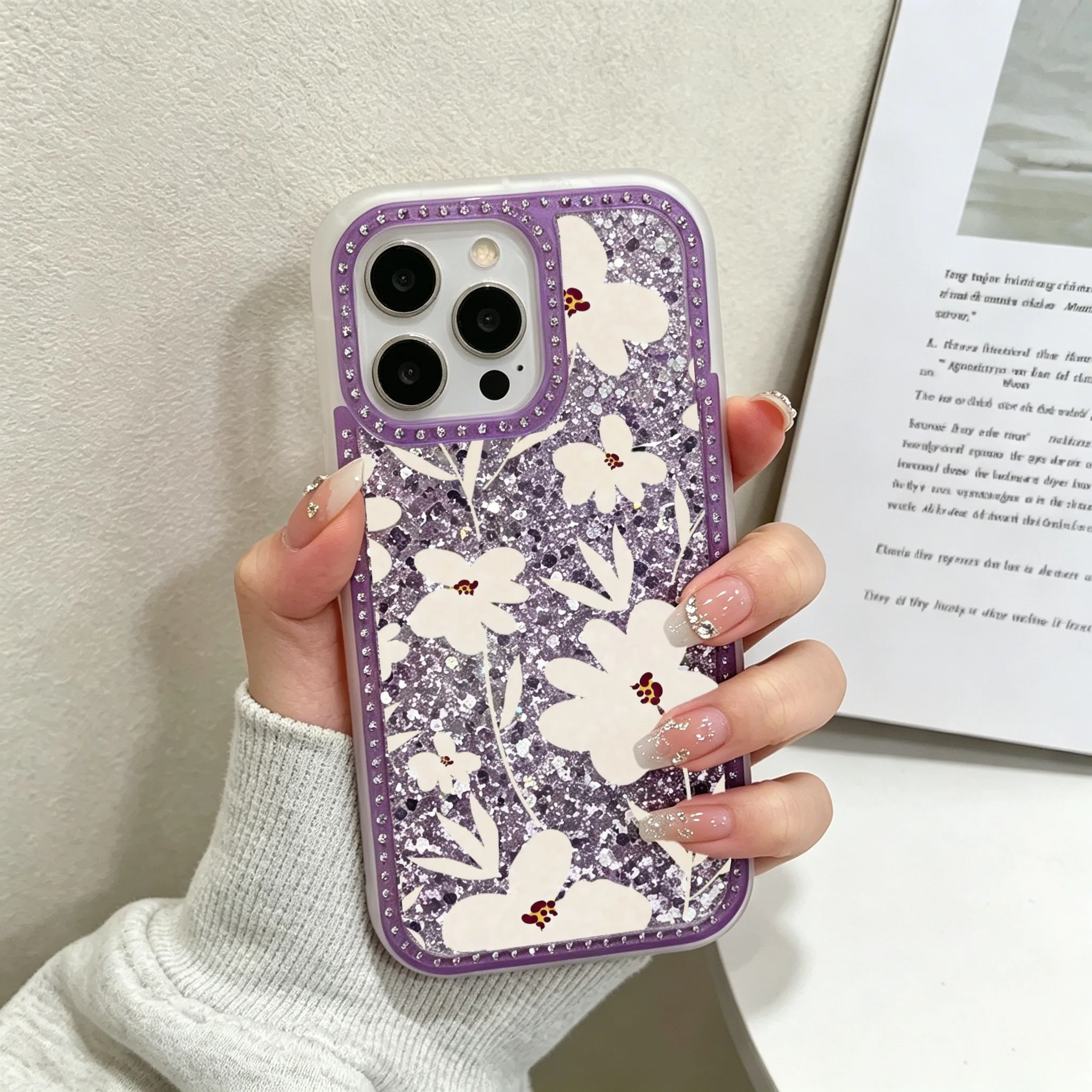 

Luxury Crystal Rhinestone Border Glitter Epoxy Filled Shockproof Phone Case, Glittery Purple Phone Case, White Floral Pattern With Rhinestone Border Soft TPU Frame Hard PC Glitter Back Protective Cover Compatible with iPhone 11/12/13/14/15/16 Series