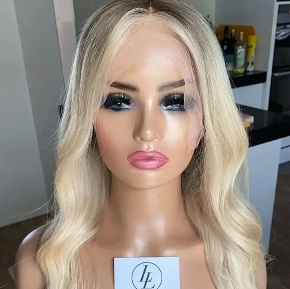 Peruka syntetyczna typu lace front z ciemnymi odrostami, jasnoblondowa peruka, peruka z falą body wave, naturalna peruka falowana, wstępnie wyskubana linia włosów, blond peruka z miękką koronką.
