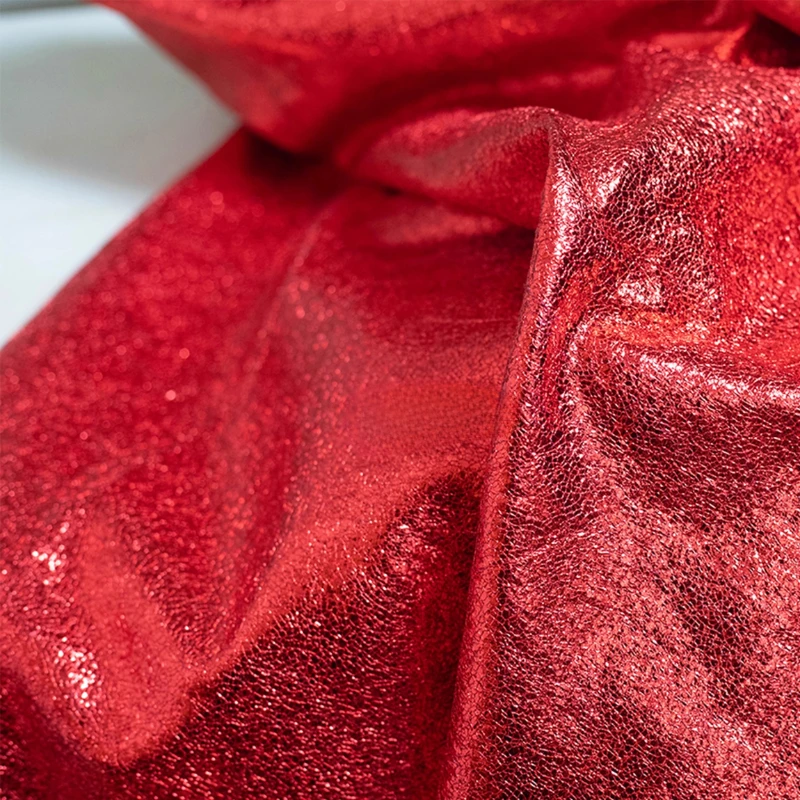 

Красная металлическая кожаная ткань с блестящим блестящим покрытием, потрескавшаяся чешуя, текстура стекла, как дизайнерский материал для курток, сумок