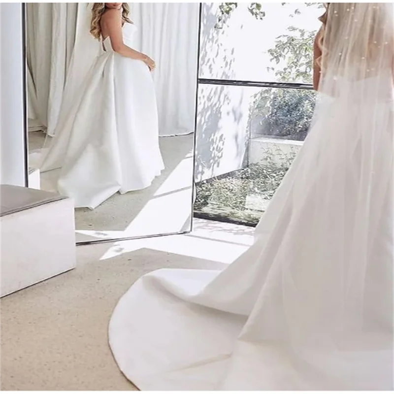 Maßgeschneiderte Falten-Prinzessin-weiße Brautkleider 2026 für die Braut, trägerloses, ärmelloses Damen-Ball-Brautkleid aus Satin mit Schleppe