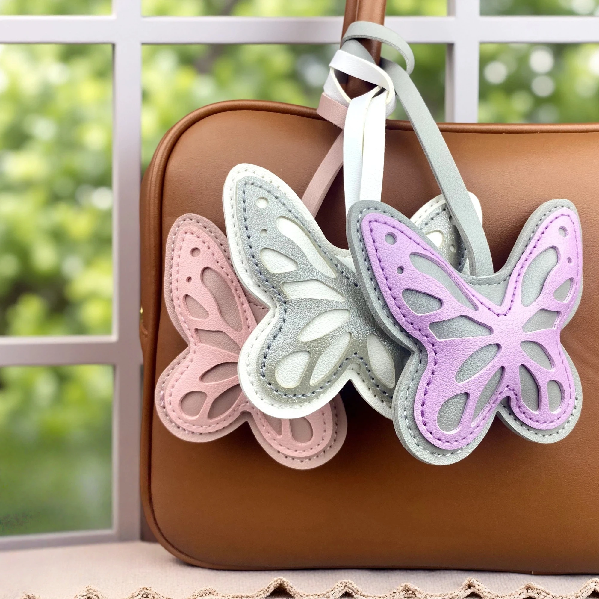 Elegante juego de llaveros y adornos para bolso con motivos florales y de mariposas, fabricados en cuero sintético, con flores y un colgante de mariposa cortado con láser, y un adorno artístico para bolso con forma de