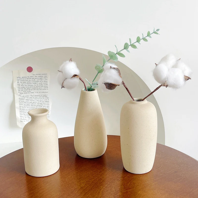 Three beige ceramic vase set on top of a wooden table