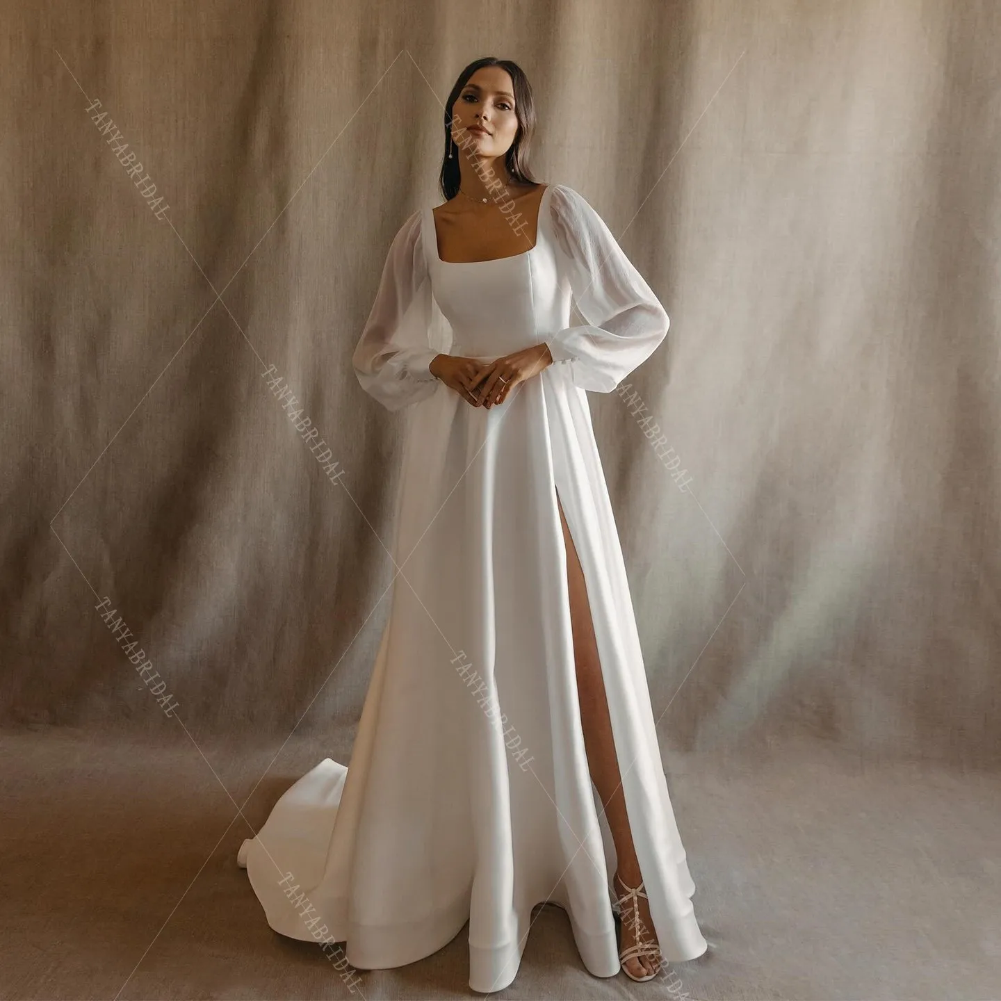 ชุดแต่งงานผ้าซาตินคอเหลี่ยม แขนยาว ทรงเอ ผ่าข้างสูง ชายกระโปรงยาวลากพื้น ดีไซน์หรูหรา