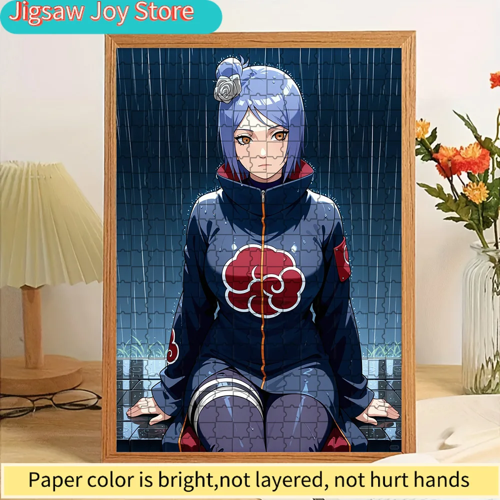 Rompecabezas de Papel de Alta Calidad con Diseño de Anime: Konan con Capa de Akatsuki Arrodillada en un Suelo Mojado con Azulejos en una Escena Lluviosa con Hierba Verde Vivi