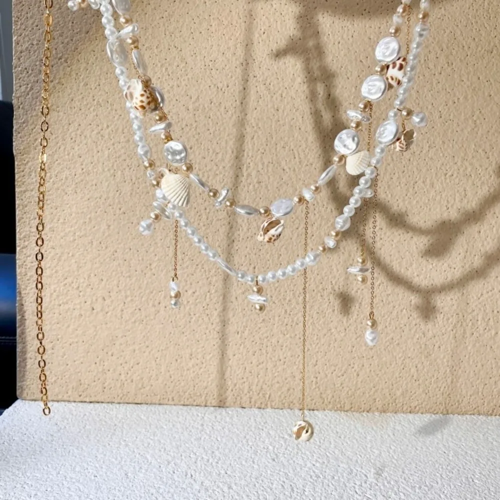 Modne łańcuszki na talię z muszelek, frędzli i pereł, eleganckie łańcuszki biodrowe w stylu boho, uniwersalne łańcuszki na brzuch, akcesoria do sukienek w stylu wakacyjnym.