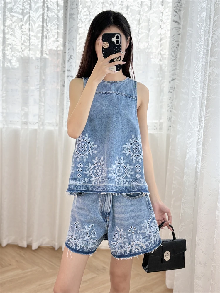 A stylish outfit featuring a blue, niche denim vest with heavy embroidery and fringed shorts