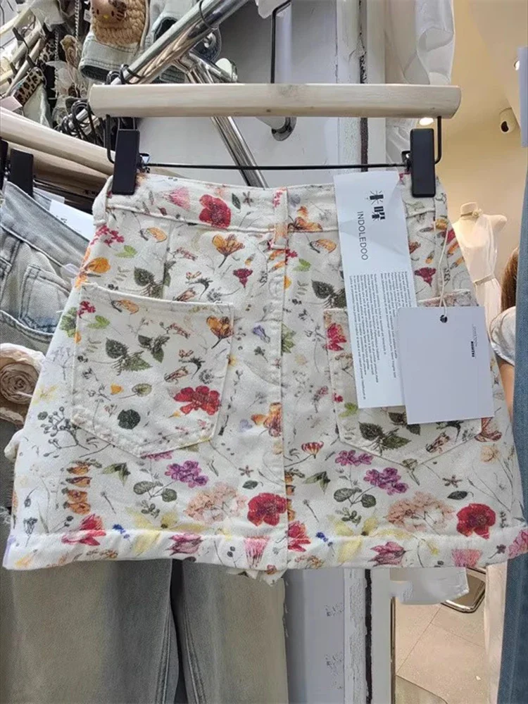 تنورة قصيرة من قماش الدنيم مطبوعة بالزهور البيضاء للنساء في الصيف من تنورة حلوة وعالية الخصر لتنحيف الخصر وتعانق الورك