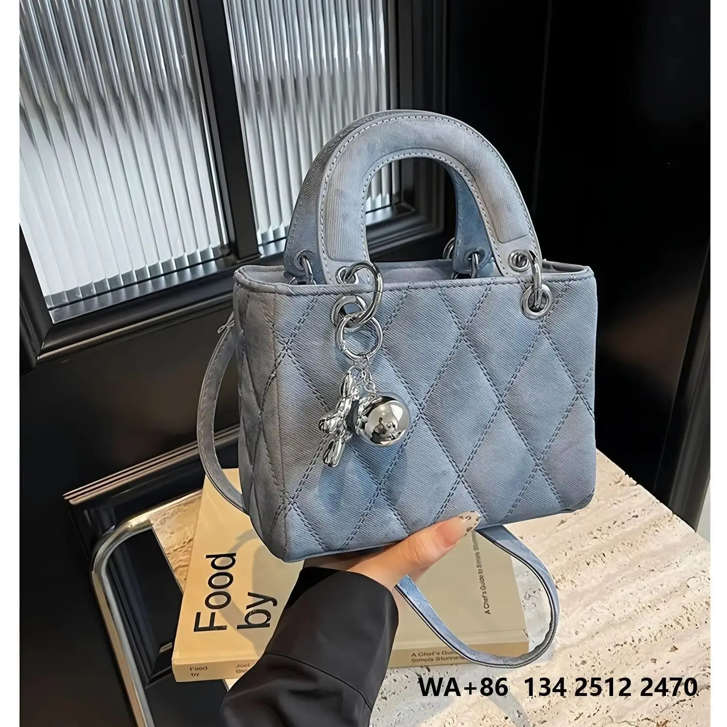 Light blue washed fabric diamond-quilted mini tote bag with a top handle, detachable thin crossbody strap, and silver bear and ball charm.