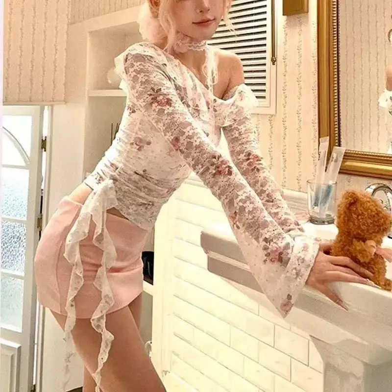 

Комплект из двух предметов: полупрозрачный кружевной топ с открытыми плечами, рюшами и принтом цвета шампанского, и розовая облегающая мини-юбка.