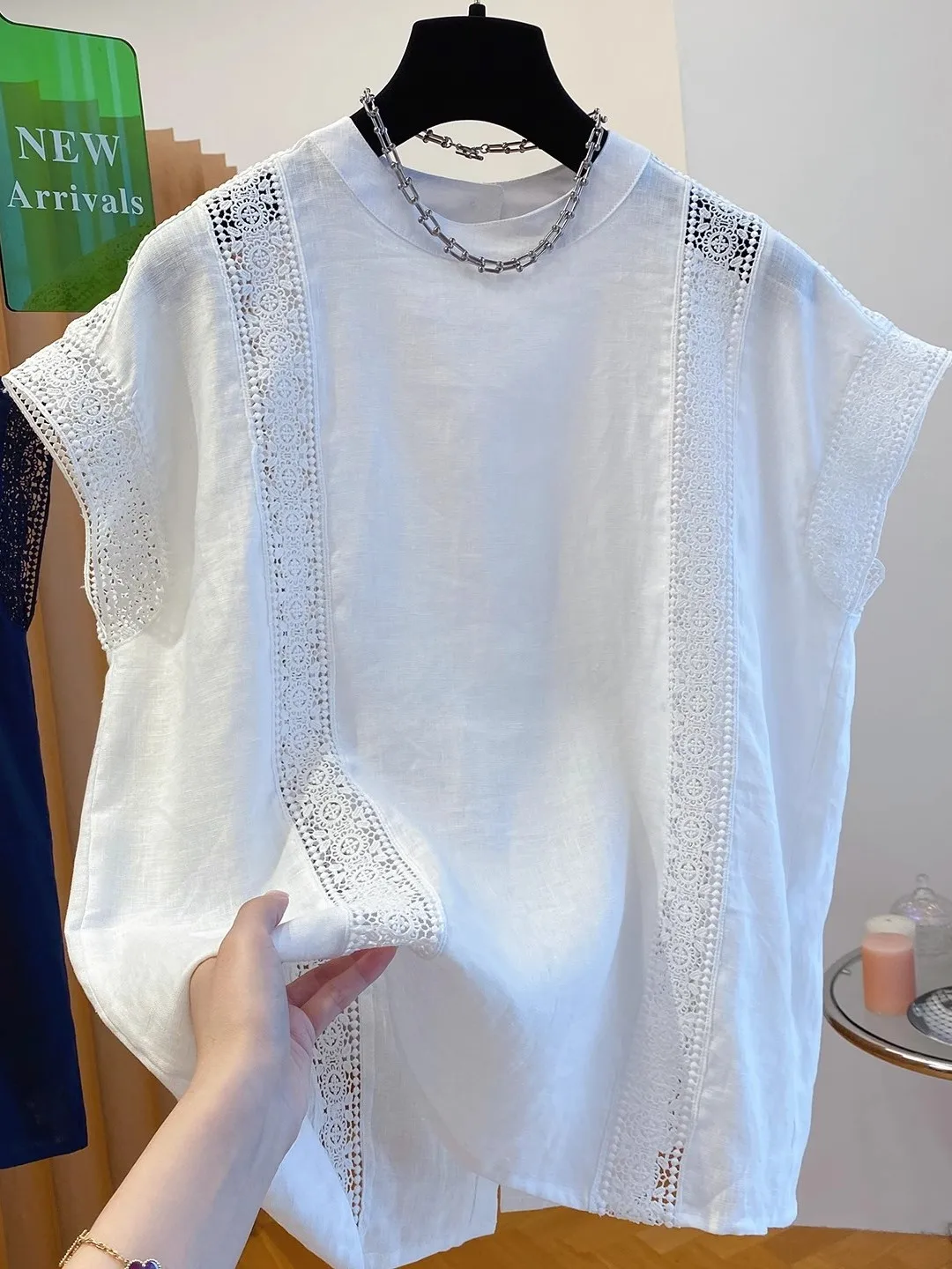 Letnia, codzienna bluzka damska z bawełny i lnu, z ażurowym wzorem kwiatowym, luźny krój, okrągły dekolt, biała, z falbankami.