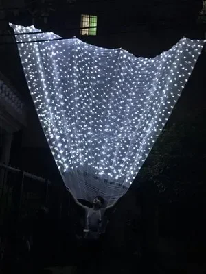 

Os trajes são grandes e exagerados, e os adereços de lírio são grandes asas das pétalas adereços na parte de trás da exposição p