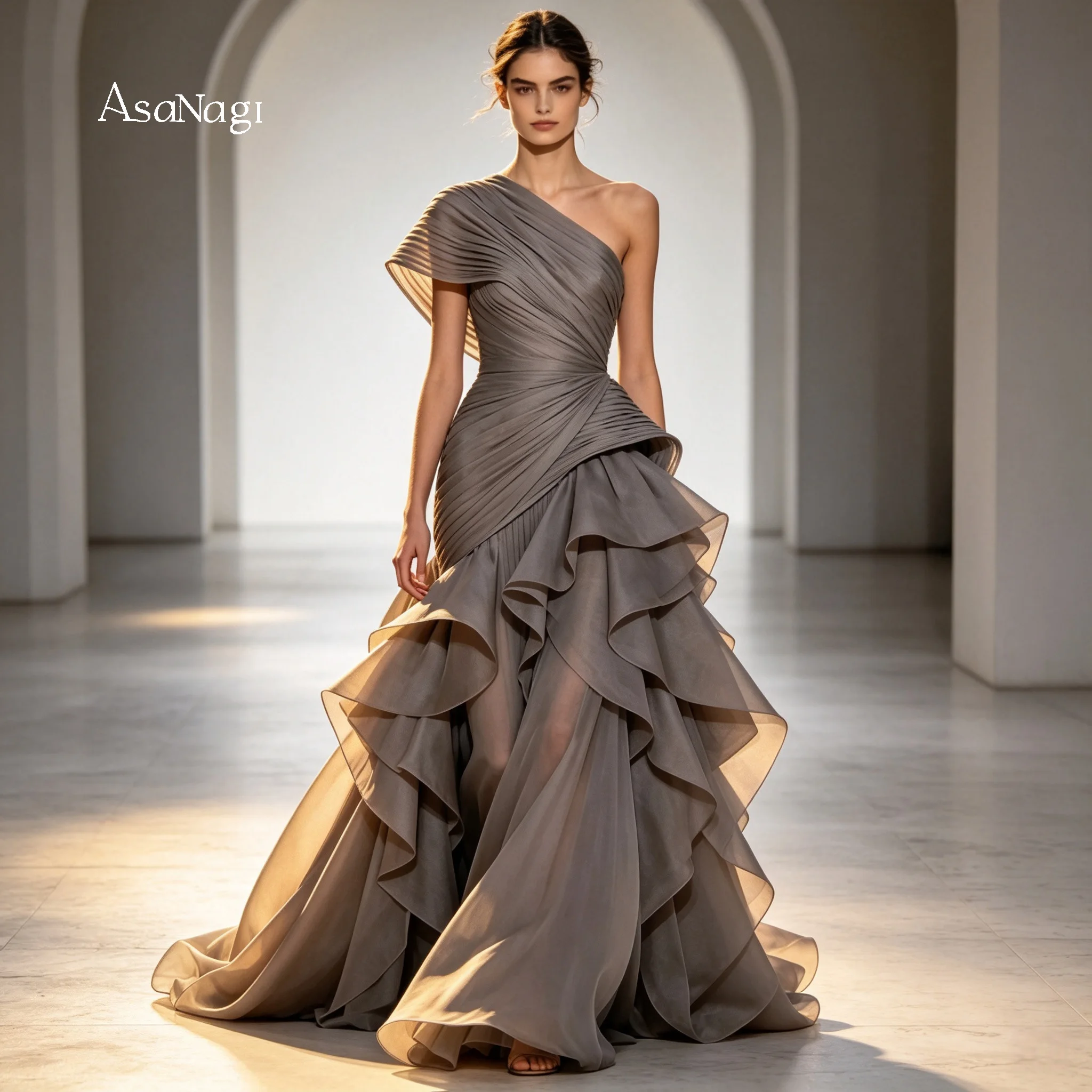 Vestido de noche plisado de un solo hombro en gris neblinado con falda de gasa con volantes en capas. Vestido de noche minimalista para eventos formales.