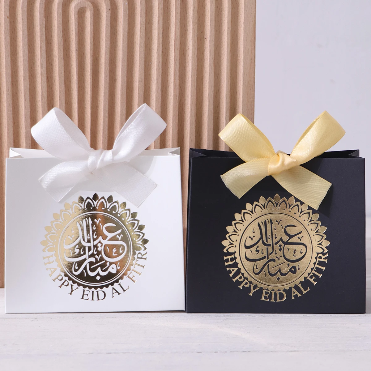 5 exquisitas y compactas cajas de regalo para Eid, cada una con elegantes colores principales en negro, verde lujoso y blanco puro, adornadas con delicada escritura árabe y círculos dorados, y atadas con lujosas cintas doradas y plateadas. Estas cajas de regalo están hechas con materiales de alta calidad, lo que las convierte en ideales para guardar dulces, chocolates y pequeños regalos, y también son un excelente empaque para ocasiones especiales.