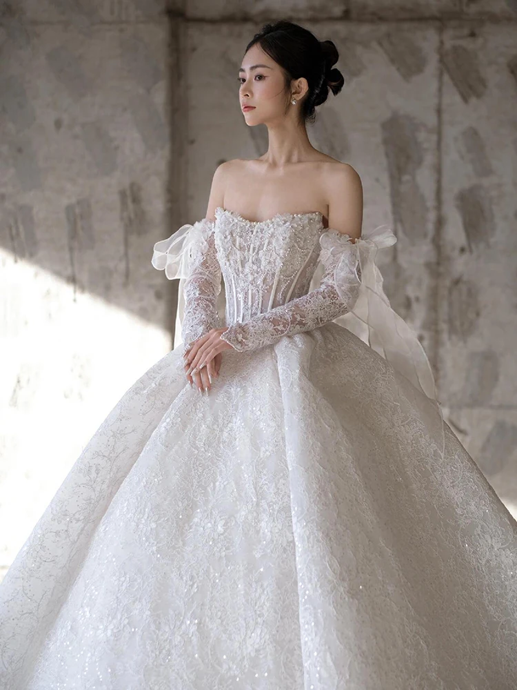 Luxuriöse glitzernde Brautkleider mit langen Ärmeln und trägerlosem Oberteil. Hochzeitskleid für Bräute. Hochwertiges, glänzendes Hochzeitskleid nach Maß