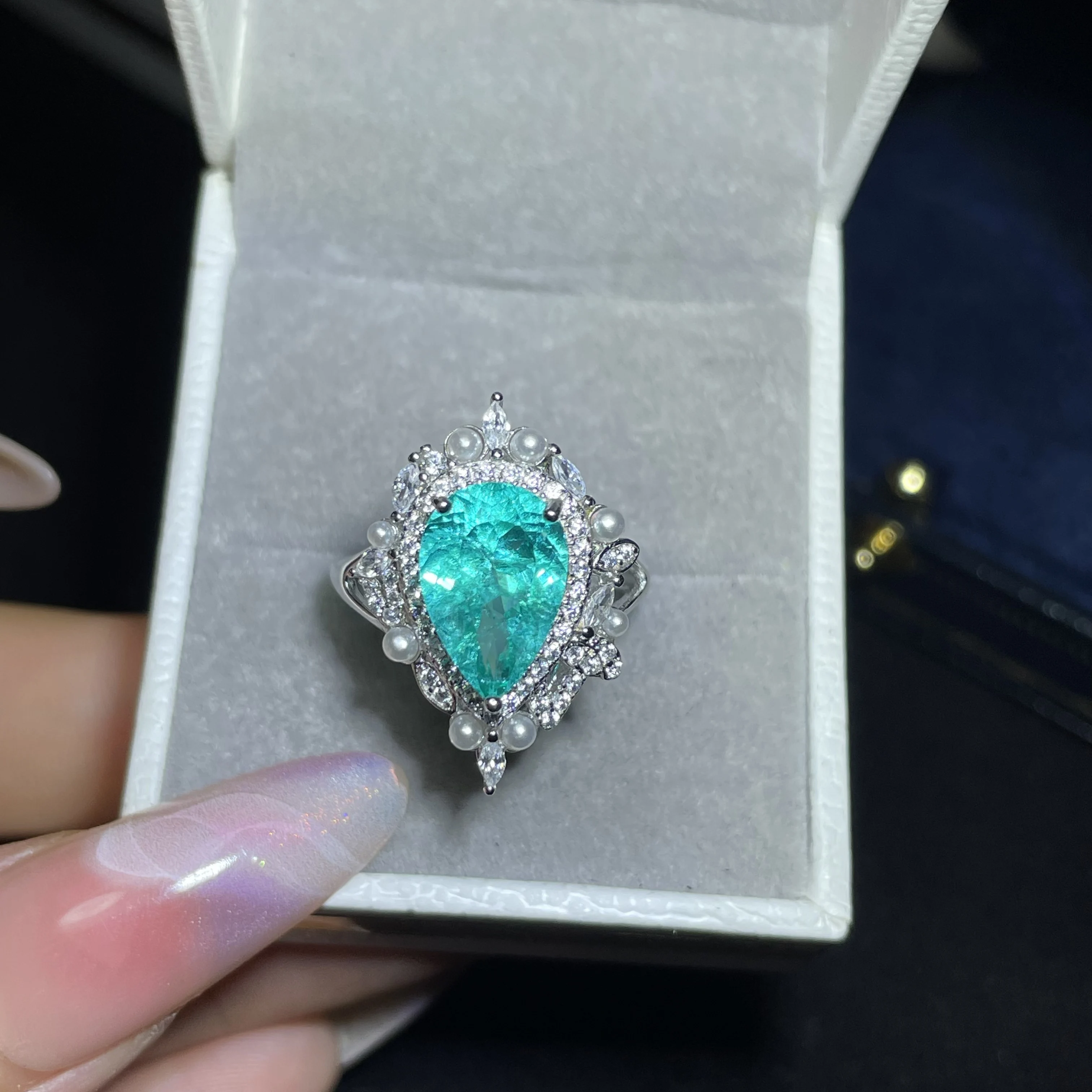 Highly saturated sky blue Paraiba diamond engagement ring in pear shape, with a sophisticated design for women
