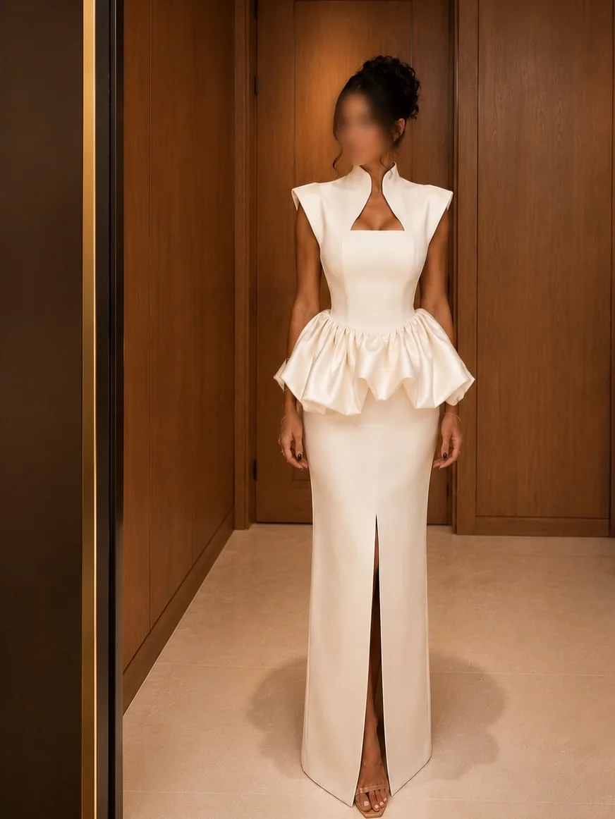 Vestido largo formal de satén brillante color marfil con cuello mandarín, abertura en el pecho, sin mangas, peplum voluminoso con volantes y cintura alta con abertura.