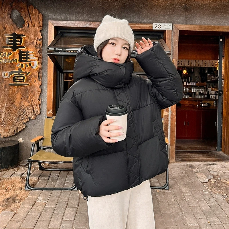 เสื้อแจ็คเก็ตฤดูหนาวผู้หญิงแบบใหม่ปี 2025 เสื้อโค้ทผ้าฝ้ายหนาอุ่นแบบสั้นสไตล์เกาหลี เสื้อพาร์ก้าไซส์ใหญ่หลวมๆ มีฮู้ดสำหรับฤดูหนาว เสื้อโค้ทพื้นฐาน