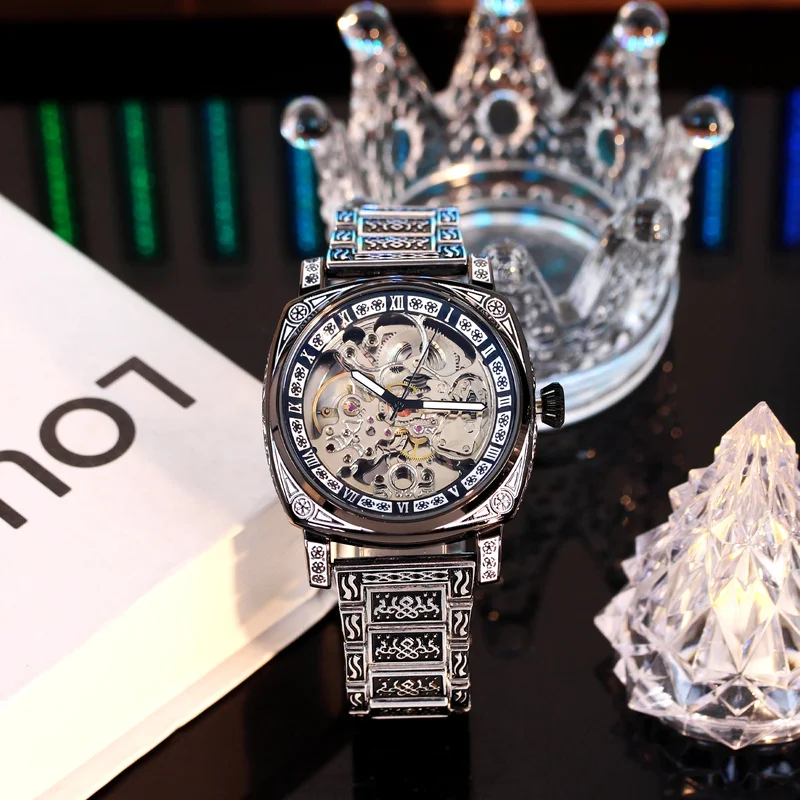 

A men's silver and black steel strap fashion finely carved vintage patterned hollow automatic mechanical watch