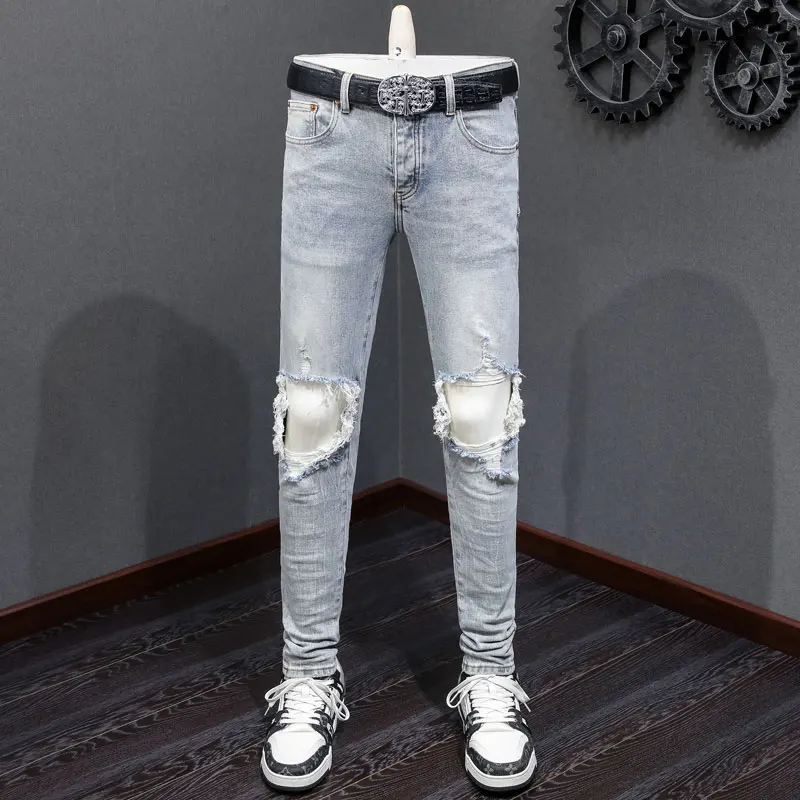 

Designer's fashionable new light blue jeans with stretch, slim fit, ripped holes, white patches, washed with water, nostalgic pa