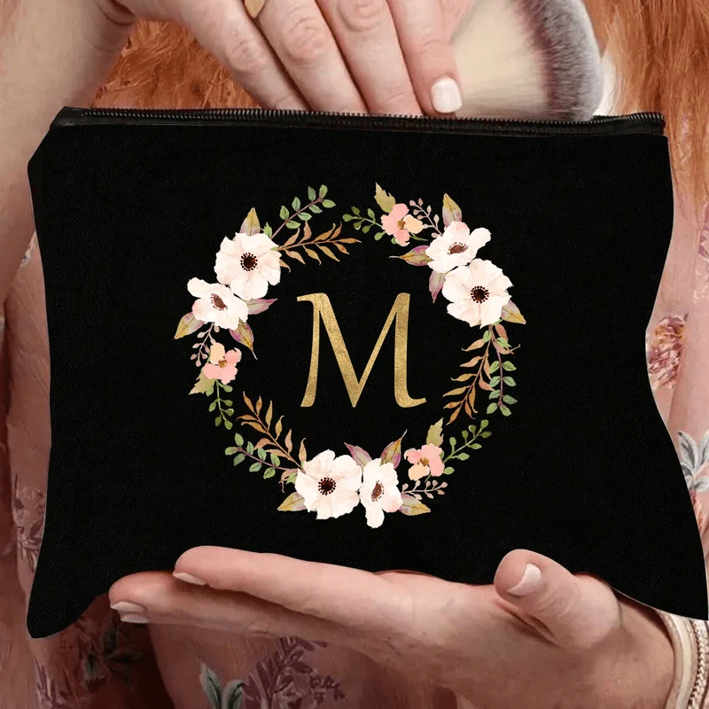 An Elegant Floral Makeup Bag Featuring A Golden 'M' Letter - Designed With Black And Beige Flowers This Lightweight And Durable