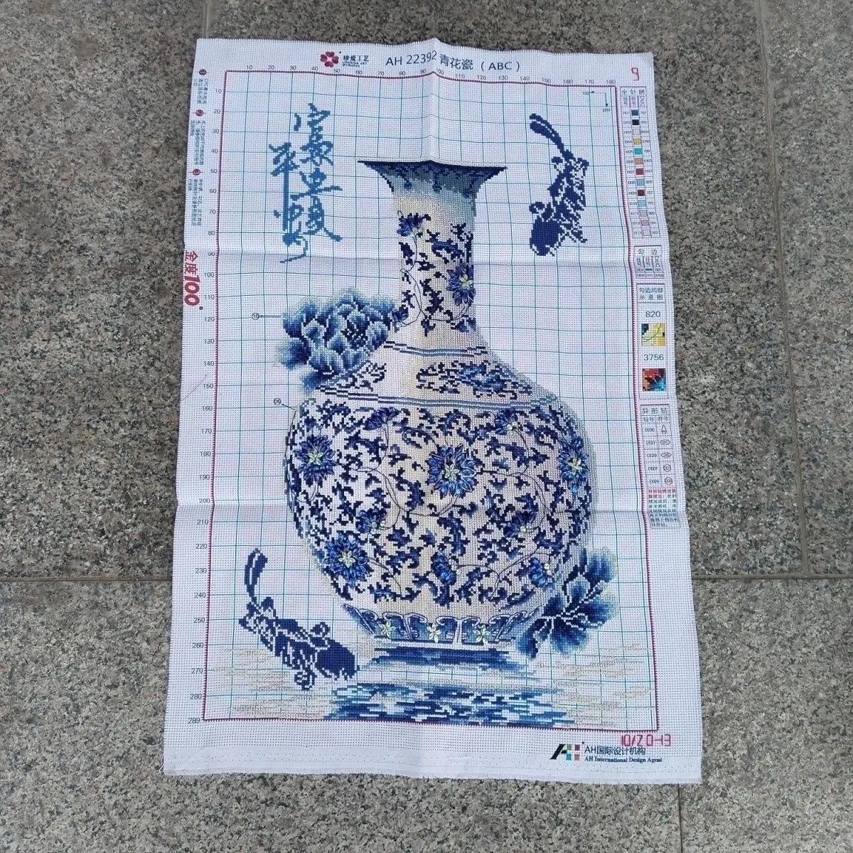 A handmade cross stitch finished product with blue and white porcelain bottles, blue diamonds, peace, security, wealth, and