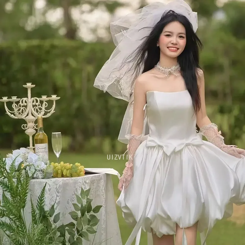 فستان زفاف قصير بسيط بيج بدون حمالات على شكل حرف a من الساتان بفيونكة قصيرة كورية لالتقاط الصور فستان زفاف مخصص للحفلات وأعياد الميلاد