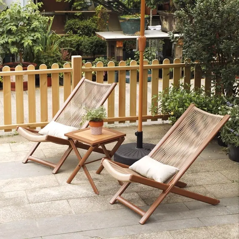 Heritage wood-frame folding rattan lounger with handrails on a garden balcony
