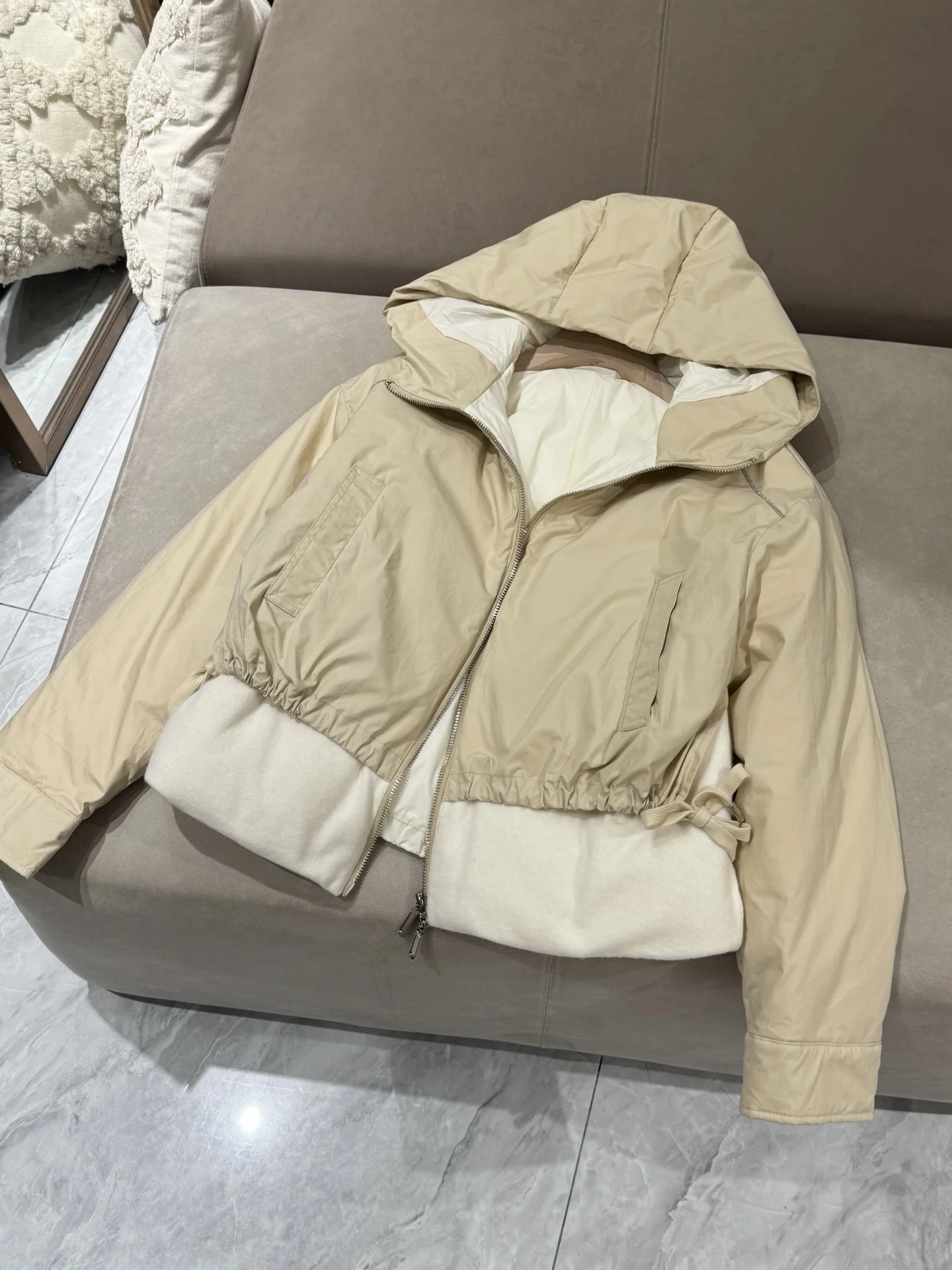 เสื้อแจ็คเก็ตขนเป็ดผสมแคชเมียร์ ขนสัตว์ และผ้าไหม พร้อมฮู้ด แต่งโซ่ประดับลูกปัด และแขนเสื้อแบบดรอปชอลเดอร์ เพื่อทรงสวยสง่า