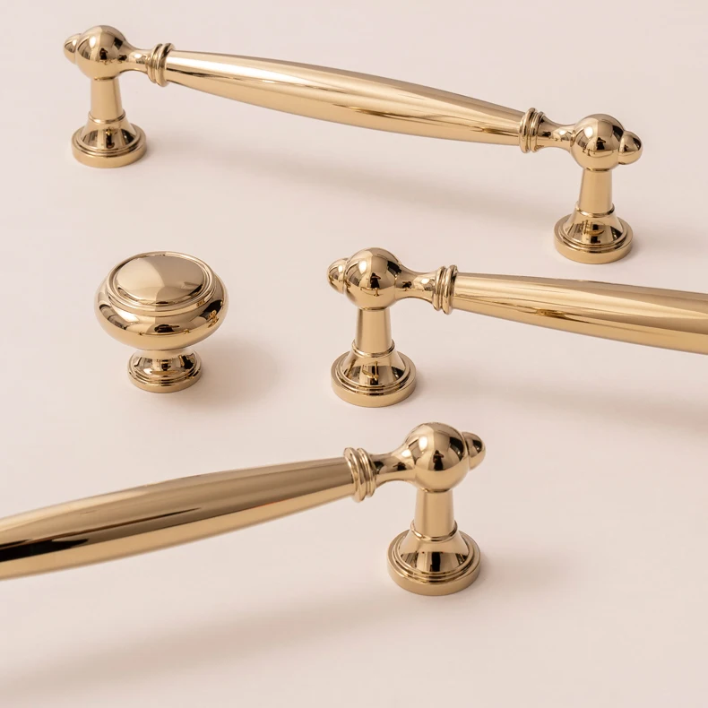 Gold bar handles and matching round knob on a light surface