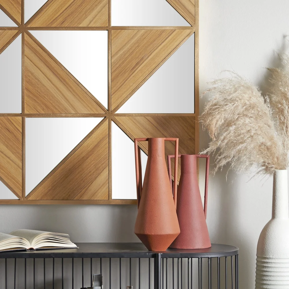 مجموعة مزهرية معدنية مكونة من مزهرتين مزخرفين باللون البرتقالي الحديث مع مقابض وحوامل زهور على سطح الطاولة بتصميم بسيط وملمسة نهائية من الصدأ