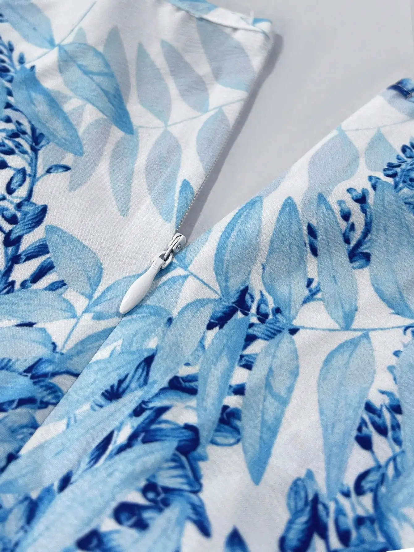 Damska niebieska sukienka maxi w kwiaty z dekoltem w serek, wycięciami i falbankami na rękawach, idealna na wakacje na plaży.