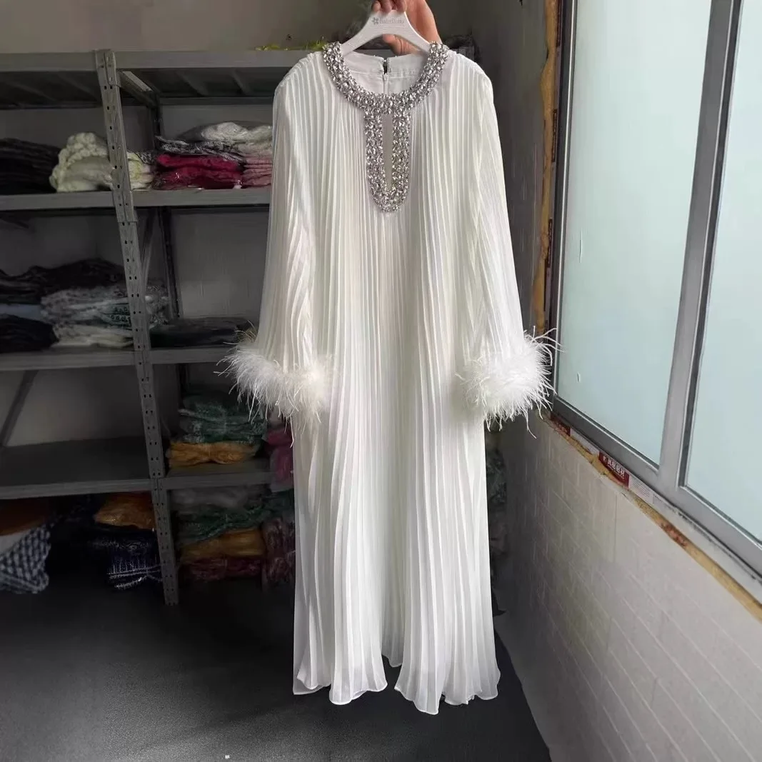 

Длинное платье с богатой отделкой и расклешенной юбкой, с завышенной талией, из полиэстеровой ткани, с плиссировкой и отделкой из перьев.