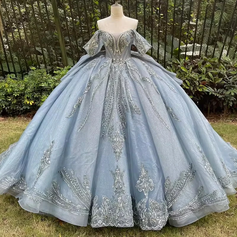 فساتين Quinceanera باللون الأزرق الفاتح اللامع ثوب حفلة قبالة الكتف مزين بالدانتيل مطرز بفيونكة مشد متدرج تول حفلة عيد ميلاد سوي