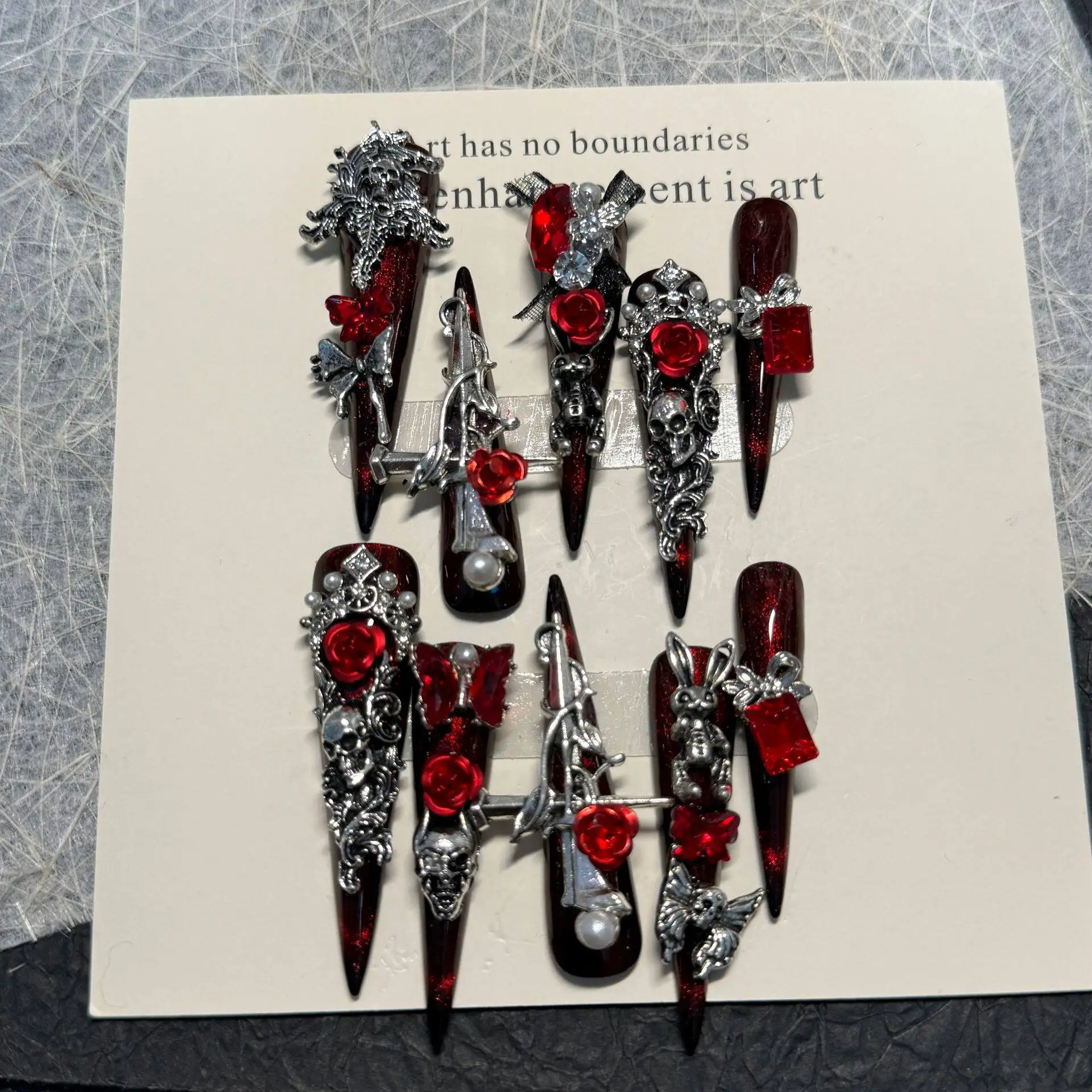 

Темно-готический роскошный крово-красный 3D пресс на ногтях Металлический декор Металлический череп Розово-красный тон горного хрусталя Серебряная лоза Gem Cluster