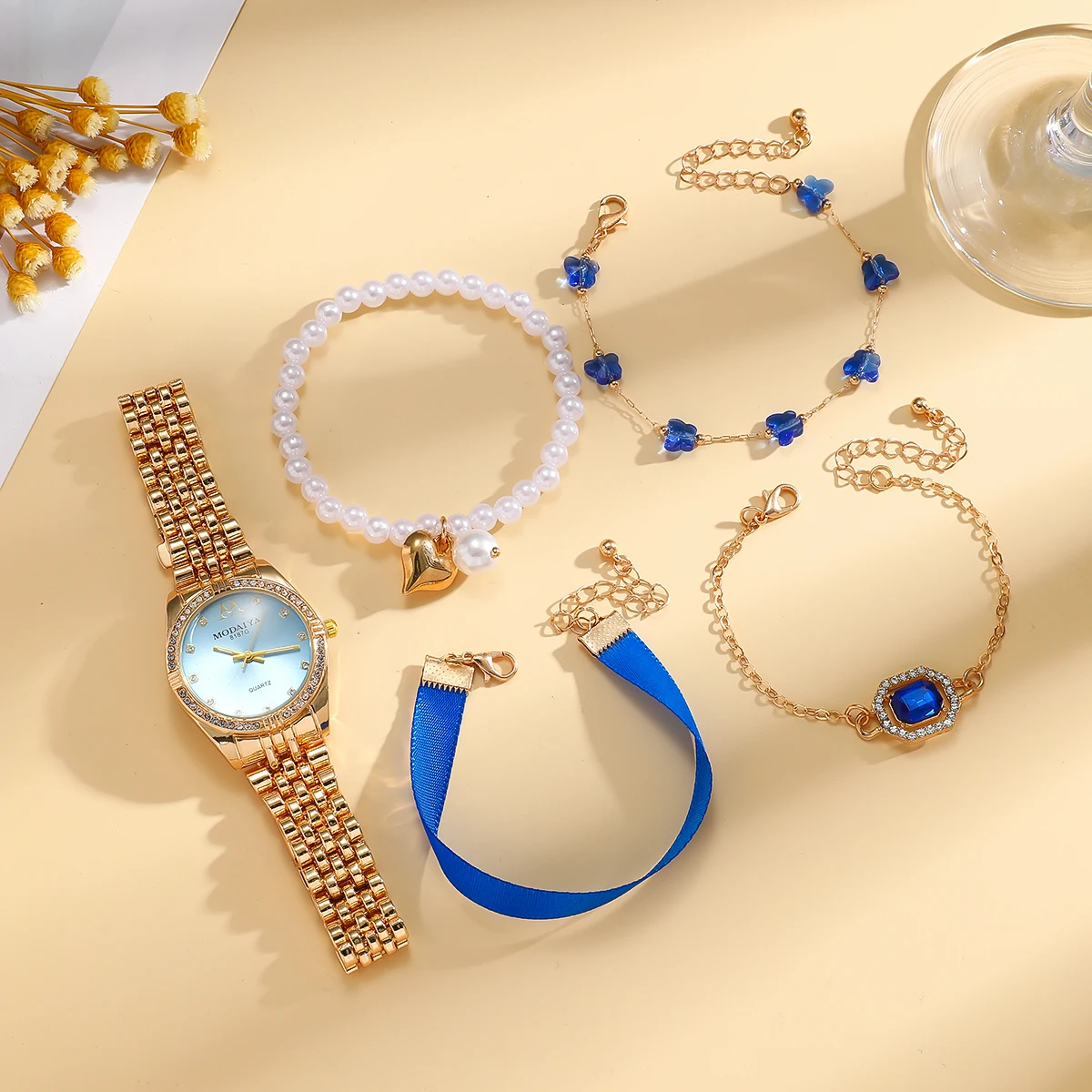 

Роскошный набор: золотые часы с синими драгоценными камнями и украшения - часы с синим циферблатом, инкрустированные стразами, многослойный браслет с синими камнями, жемчужное колье.