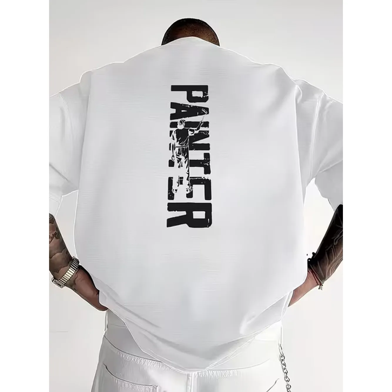 Camiseta de Pintor de Manga Larga Negra con Estampado Vertical Blanco y Letras, Figura de Pintor en la Espalda, Reloj Plateado Tatuado, Pantalones Blancos con Detalle de Cadena y Bolsillo, Camiseta Casual de Moda para Amantes del Arte