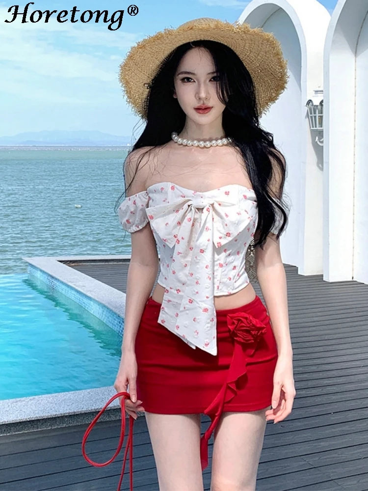 

Женский комплект из 2 предметов: белый топ с цветочным принтом, открытыми плечами и бантом, и красная мини-юбка с цветочным узором. Идеальный летний пляжный наряд для отпуска.