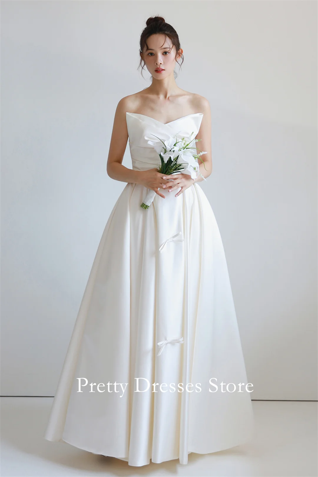 

Элегантные атласные свадебные платья трапециевидной формы цвета слоновой кости без бретелек в стиле садового цвета со стразами и корсетом с бантом, вечерние для женщин