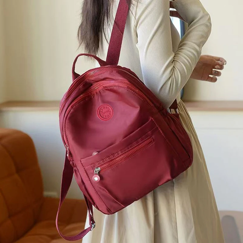 حقيبة ظهر بتصميم محايد للرجال والنساء، مناسبة للسفر والتصوير الفوتوغرافي مصنوعة من مادة النايلون، مع تصميم شعار دائري.