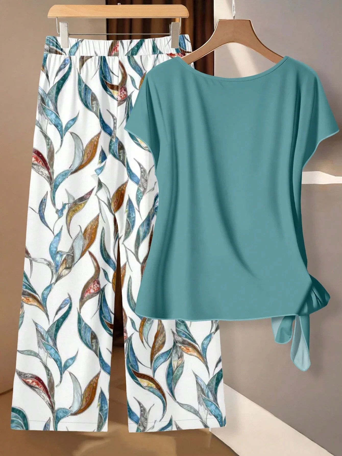

Однотонный бирюзовый топ с рукавами-крылышками и узлом сбоку и брюки с цветочным принтом и принтом в виде листьев, комплект из двух предметов