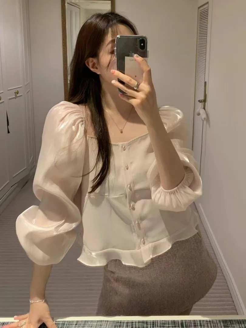 قميص أنيق بياقة مربعة وأكمام منتفخة مع أزرار دقيقة وحواف دانتيل، يضفي أجواء نهاية العام، مزين باللؤلؤ واللمعان وأكمام طويلة