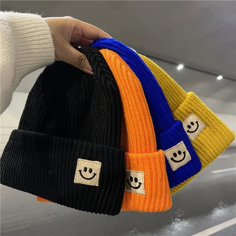 Gorro de lana de punto cálido para mujer, gorro de punto negro con protección para los oídos que combina con todo, a la moda, con logotipo de cara sonriente, otoño e invierno