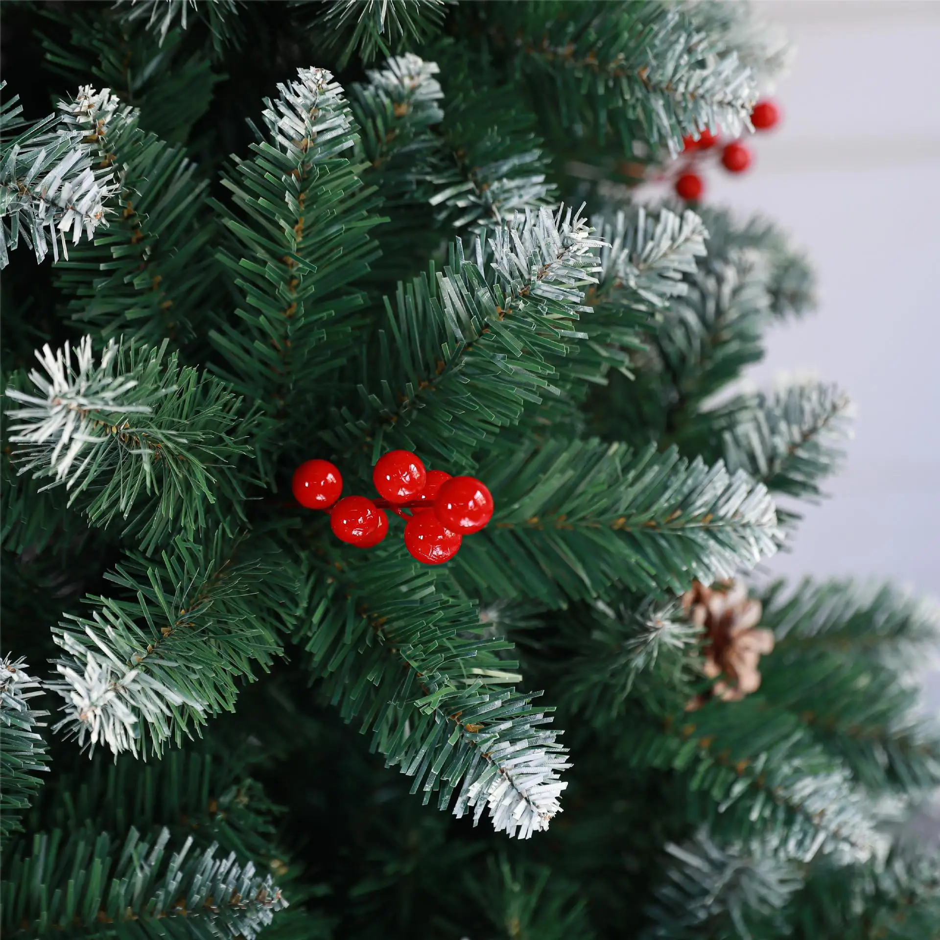 Artificial green Christmas tree with red berries and pine cones