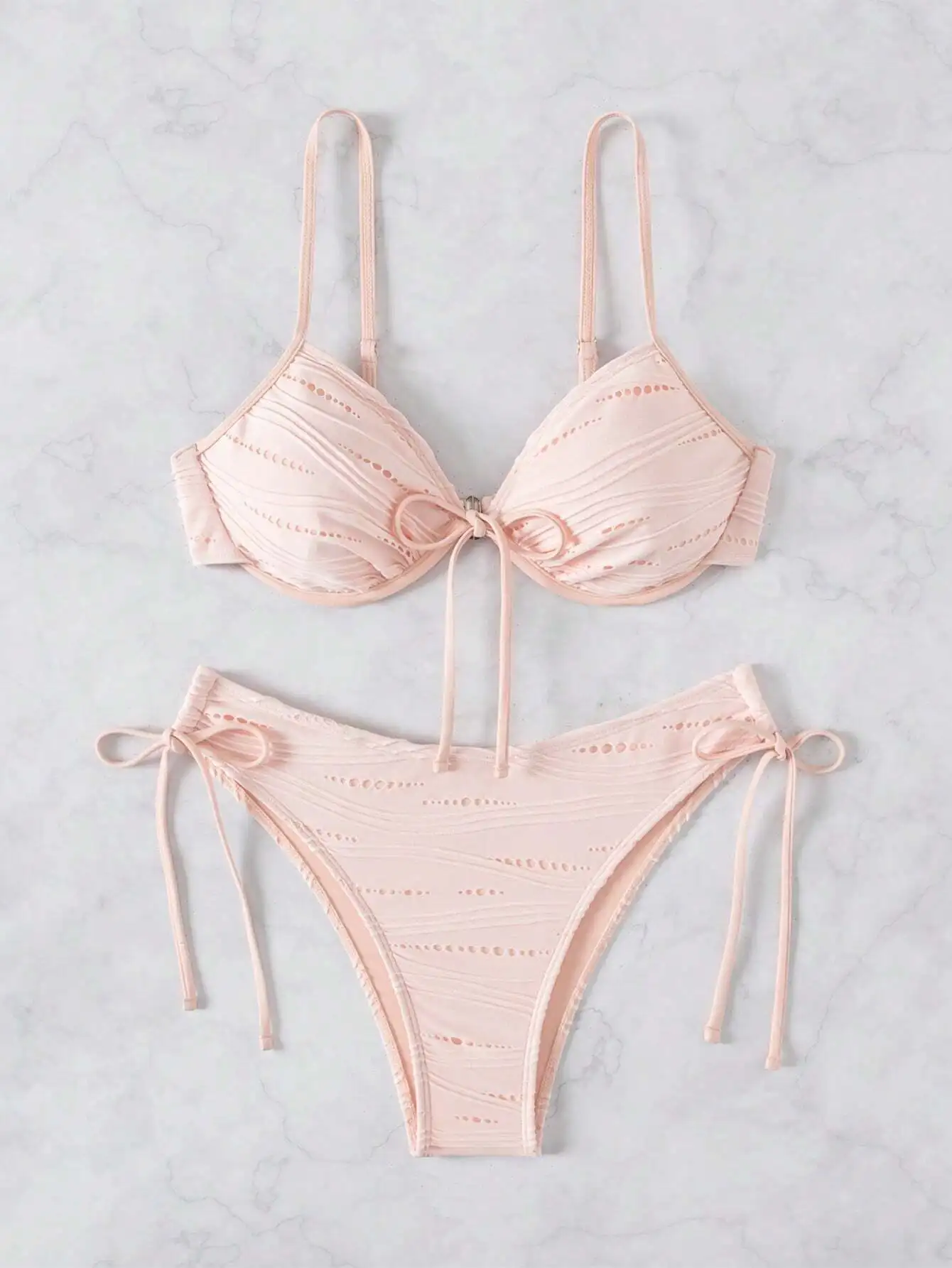 

Пастельно-розовый комплект бикини на бретельках с бантом и завязками по бокам, с высокой посадкой и вырезами.