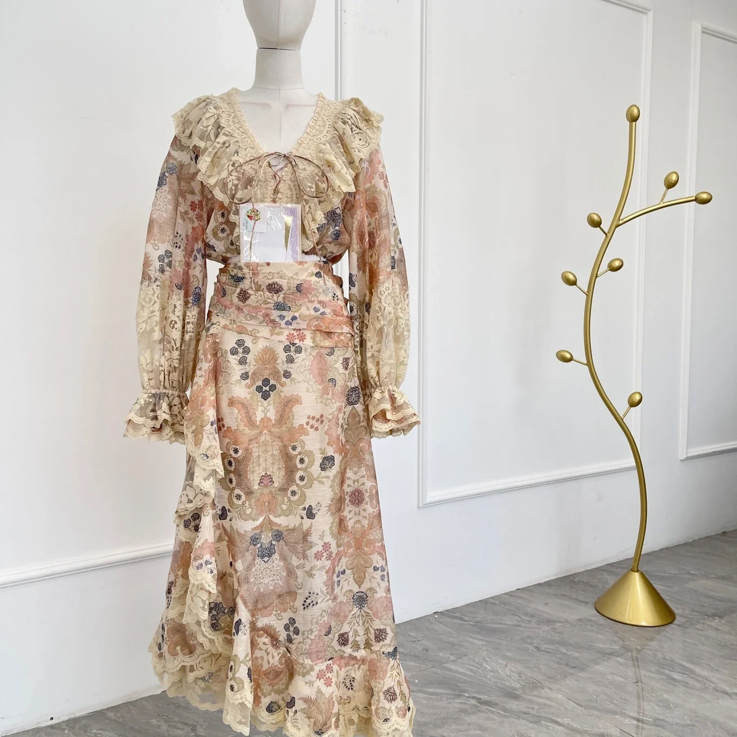 

Бежевый комплект: блузка с цветочным принтом, кружевом, длинными рукавами и V-образным вырезом, а также юбка миди с асимметричным подолом, новинка 2025 года